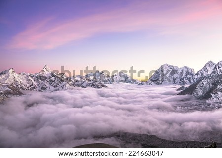 Picturesque mountain valley filled with curly clouds at sunset. Sacred Ama Dablam peak (6814 m) dominates on the left. Nepal, Himalayas. Canon 5D Mk II. 