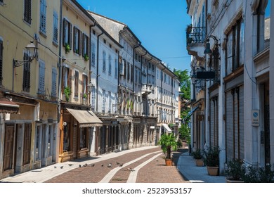 Picturesque narrow street lined with colorful buildings, shuttered windows, and traditional architecture in Gorizia's old town. Decorative lamps and potted plants add to the quaint atmosphere - Powered by Shutterstock