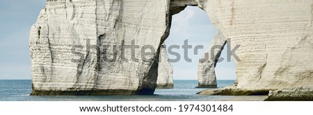 Picturesque panoramic low angle view of the Etretat white cliffs. Dramatic sky, atmospheric landscape. Summer vacations in Normandy, France. Travel destination, national landmark, sightseeing, history