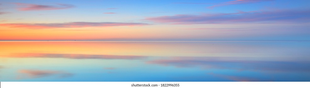 Picturesque panoramic scenery of the open Baltic sea at sunset. Symmetry reflections on the water, natural mirror. Breathtaking view. Winter seascape. Pure nature, seasons, climate change - Shutterstock ID 1822996355