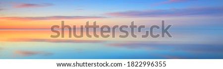Picturesque panoramic scenery of the open Baltic sea at sunset. Symmetry reflections on the water, natural mirror. Breathtaking view. Winter seascape. Pure nature, seasons, climate change