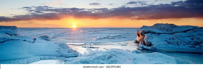 Picturesque panoramic scenery of the snowy Baltic sea shore at sunset,ice fragments close-up. Breathtaking view. Winter seascape. Pure nature, seasons, climate change