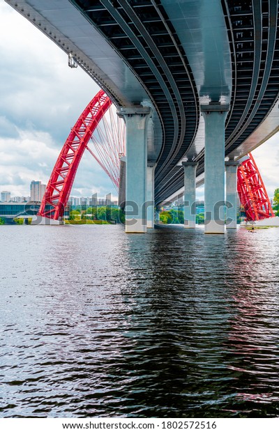 Picturesque red bridge over the\
river in Moscow, photo taken under the bridge with metal holding\
beams