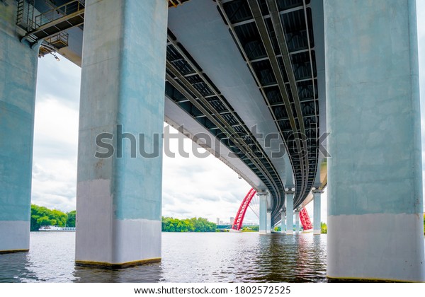 Picturesque red bridge over the\
river in Moscow, photo taken under the bridge with metal holding\
beams