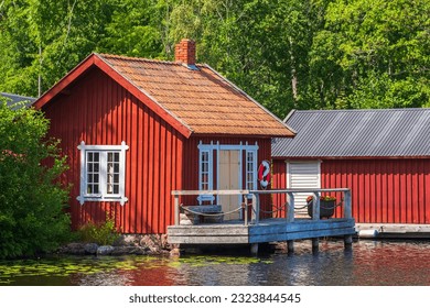 Picturesque red cottage by a lake with a jetty