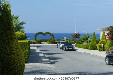 A picturesque road leads to a breathtaking view of the ocean, framed by meticulously trimmed hedges and lush greenery, inviting visitors to explore the beauty of the coastal landscape. - Powered by Shutterstock