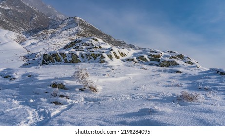 The picturesque rocks are covered with a layer of pure white snow. Footprints in snowdrifts. A picturesque mountain against the blue sky. The peak is hidden in the haze. Altai. Kalbak Tash - Shutterstock ID 2198284095