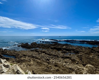 A picturesque rocky island in the ocean, with a small boat and people exploring the rocky terrain. The tranquil blue sky and water create a serene backdrop for this adventurous scene. - Powered by Shutterstock