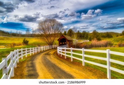 Picturesque rural road over a covered bridge. Rural fenced road. Fenced road countryside landscape. Beautiful countryside fenced road