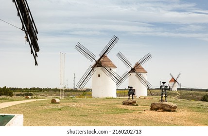 Picturesque rural spring landscape of Mota del Cuervo with row of ancient windmills and symbolic iron statues of Don Quixote and Sancho Panza set on stones by local artist, Cuenca, Spain