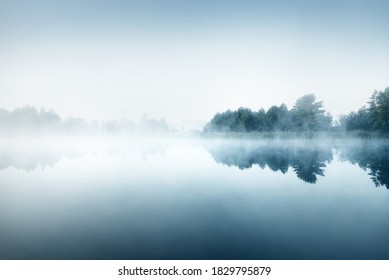 Picturesque scenery of the forest lake in a thick white fog. Reflections on the water. Dark atmospheric landscape. Fall season. Nature, ecology, environmental conservation, eco tourism
