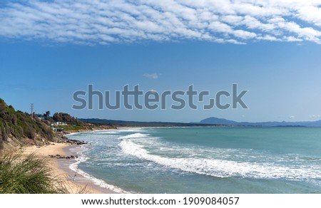 Picturesque scenery of waving sea and sandy Los Lances beach under blue sky with cirrocumulus clouds in Tarifa summer. Cadiz coastline, Andalusia, Spain