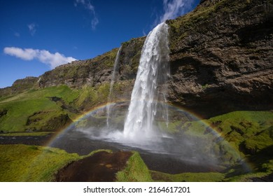 Picturesque Seljalandsfoss Waterfall In Southern Iceland. Tourist Destination With Rainbow On A Sunny Day. No People