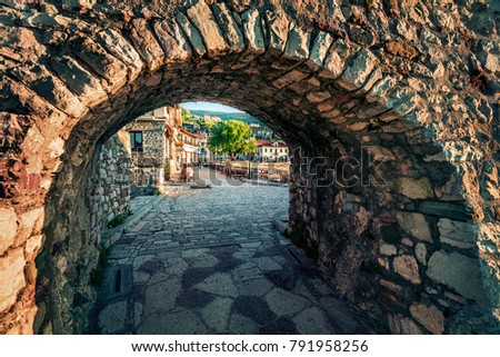 Picturesque spring view through the arch of Nafpaktos town. Beautiful morning scene of Greece small port, Europe. Traveling concept background.