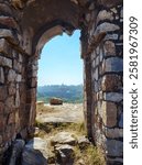 A picturesque stone archway at the ruins of an old fort provides a framed view of the surrounding terrain.  The textured stone and historic details highlight the site