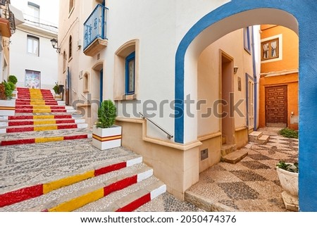 Picturesque stone pavement street with spanish flag in Calpe. Spain