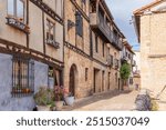 Picturesque street showcasing traditional buildings decorated with flowers in a rural town. Frías, Burgos Province, Spain