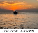 Picturesque sunset over the sea in Rovinj, Croatia. Sun is reflected in water. A speedboat yacht sails slowly in the sea at sunset.