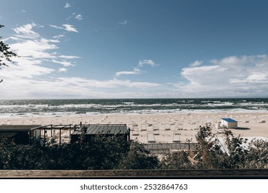 A picturesque view of a beautiful sandy beach with a bright blue lifeguard hut visible in the distance under a clear sky - Powered by Shutterstock