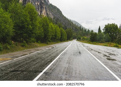 A picturesque view of the bend of the hairpin of a wet winding road through the pass, part of a mountain serpentine in cloudy weather with fog, a deserted straight mountain road on a rainy day - Powered by Shutterstock