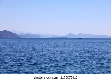 Picturesque View To Blue Sea And Mountain Island On Horizon In Mist. Calm Water Surface, Background For Traveling And Vacation