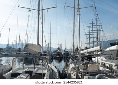 A picturesque view of a bustling marina filled with sailboats and yachts, their masts stretching toward the clear blue sky. Calm waters reflect the boats, creating a peaceful. High quality photo - Powered by Shutterstock