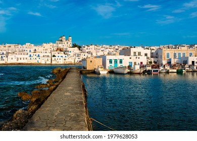 Picturesque view of Naousa town in famous tourist attraction Paros island, Greece with traditional whitewashed houses, Greek Orthodox church and moored fishing boats on sunset