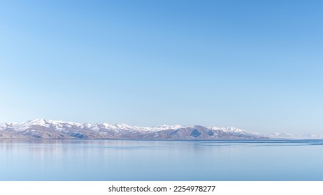 A picturesque view from a peninsula in Sevan Lake, Armenia, with high snowy mountains on the horizon. Shot in January, 2023.