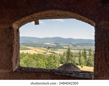 Picturesque view of rural countryside framed by an ancient stone tower window, surrounded by lush green forests and rolling hills on a summer day. High quality photo - Powered by Shutterstock