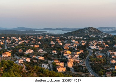 Picturesque view of small coastal town with colorful houses, winding roads, lush greenery under soft evening light. Concept of peaceful suburban living and vacation destinations. High quality photo - Powered by Shutterstock