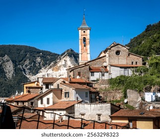 A picturesque view of a small Italian village with traditional architecture, featuring a tall clock tower and mountains in the background. - Powered by Shutterstock