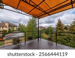 Picturesque view from the terrace balcony of the houses of an elite village surrounded by lush greenery. Terrace with tiled floor and canopy of red olycarbonate.