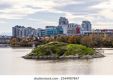 A picturesque view of Victoria, Vancouver Island, showcasing modern architecture with an island in the foreground. The calm water reflects the vibrant skyline, enhancing the beauty - Powered by Shutterstock