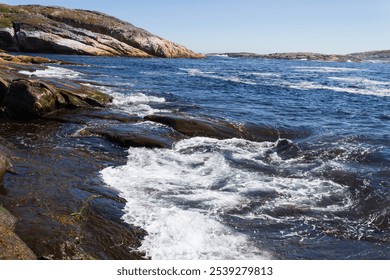 A picturesque view of waves crashing against a rocky shoreline under a clear blue sky. The tranquil ocean landscape evokes feelings of peace and serenity in nature's beauty. - Powered by Shutterstock