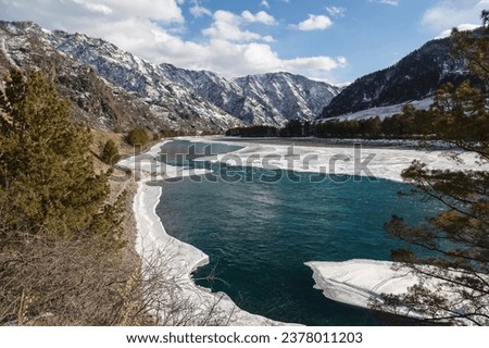 A picturesque winter landscape with snow-capped mountains, the Katun River and the taiga on the banks of the river. Gorny Altai, Russia