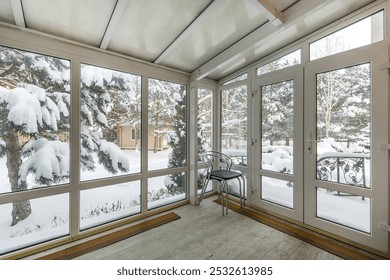 A picturesque winter landscape from the window of a glazed terrace of a country house. Snow-covered trees in the rays of the setting sun. - Powered by Shutterstock