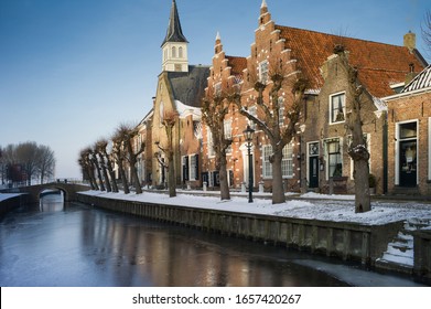 Picturesque Winter View Of A Row Of Historic Houses And Church With A Small Bridge In The Picturesque Village Of Sloten In The Netherlands