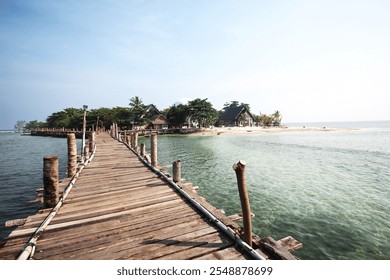 A picturesque wooden pier stretching across clear turquoise waters, leading to a serene tropical island with lush greenery and traditional villas - Powered by Shutterstock