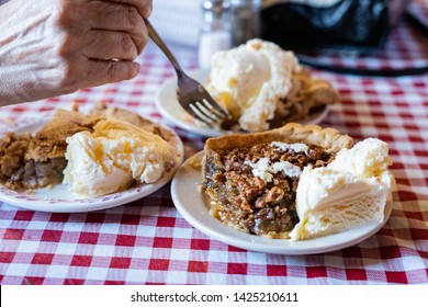 Pie A la mode State fair pies with Ice cream apple, pecan, rhubarb pies on a checkered table cloth with fork and hand