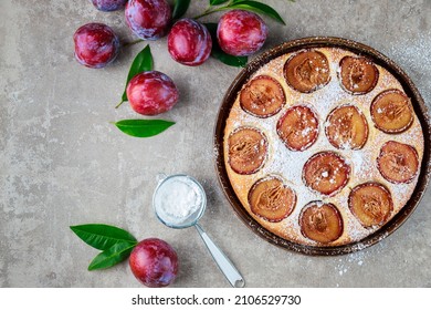 Pie With Red Fresh Plums And Green Leaves. Top View.