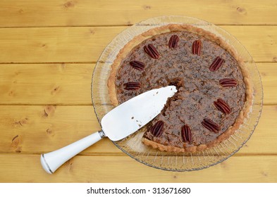 Pie server in a sliced home-made pecan pie on a wooden table