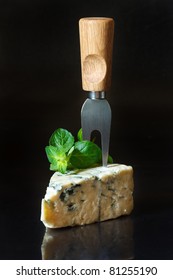 Piece Of Blue Cheese With Fork And Mint On A Black Background.