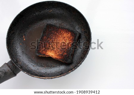 Piece of burnt toast bread on a plate on a white background. Top view, copy space