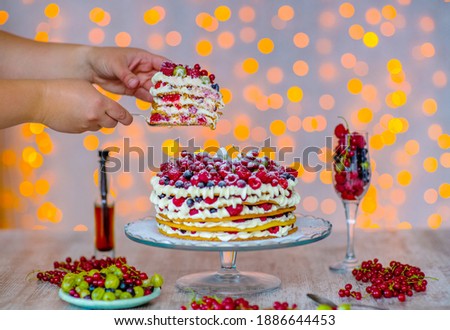 A piece of cake with berries lies on the shoulder blade of a wife clamped in her hands.