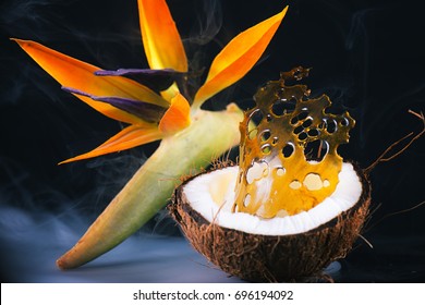 Piece Of Cannabis Shatter (marijuana Oil Concentrate) Over Coconut Half With Tropical Flower Int He Background - Medical Dispensary Concept