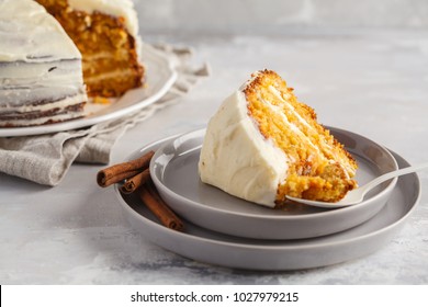 Piece of carrot homemade cake with white cream on a gray background. Festive dessert concept.