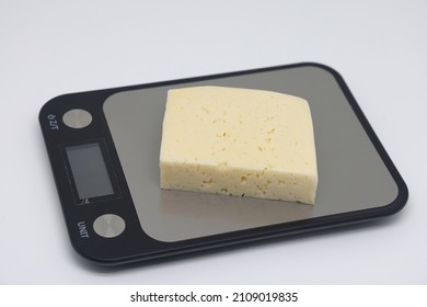 A Piece Of Cheese On The Scales. Weight Loss, Diet And Weight Control. Still Life With Healthy Food And Scales. Healthy Food. The Concept Of A Healthy Lifestyle. Weight Control During Self Isolation