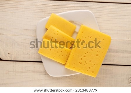 A piece of cheese on a white saucer on a wooden table, macro, top view. Foto stock © 