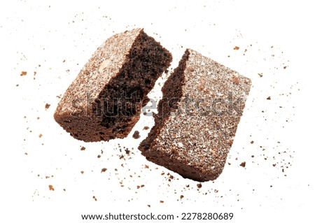 A piece of a chocolate brownie glazed with white coconut frosting snapped in half floating in mid air with crumbs around, studio shot isolated on white background 