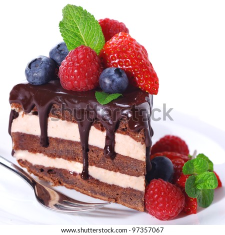 Piece of chocolate cake with icing and fresh berry on white isolated background